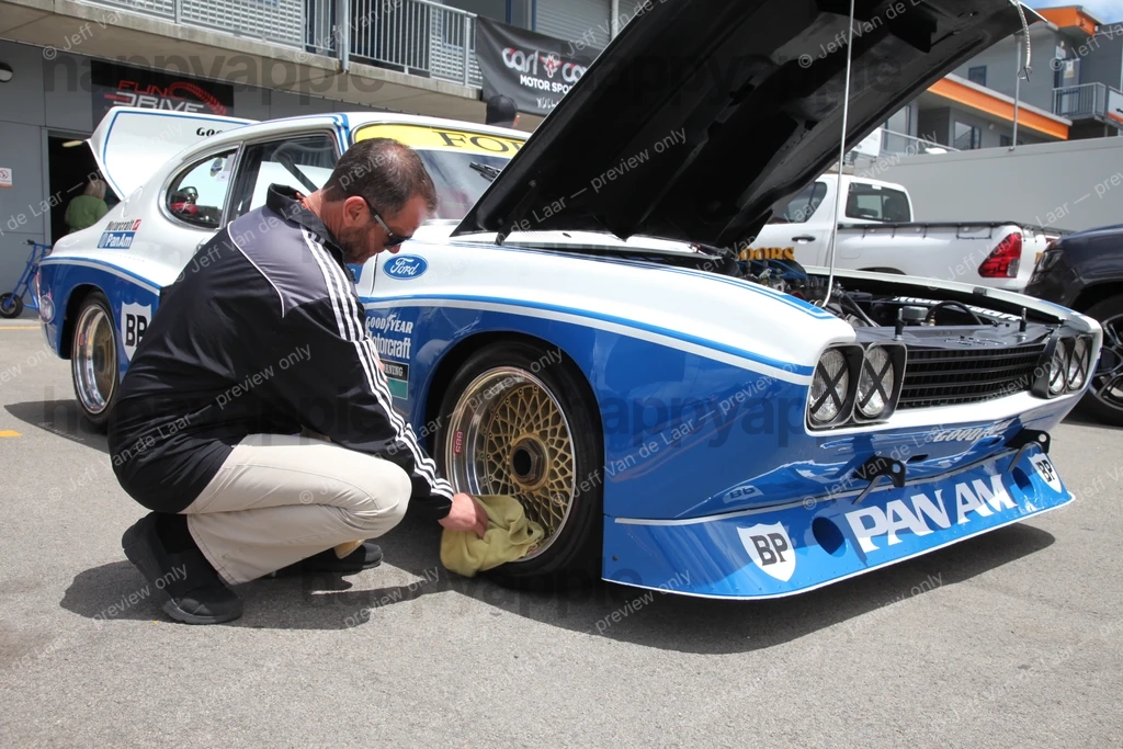 Mechanic inspecting wheel of a vintage racing car at a motorsport event — Automotive photo by Jeff Van de Laar