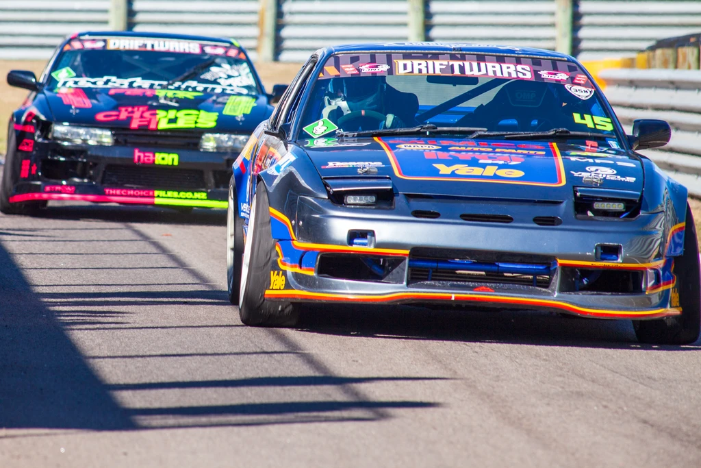 Two drift cars racing on a circuit track during a motorsport event